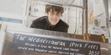 Person looking through window at food counter with menu item on the board.