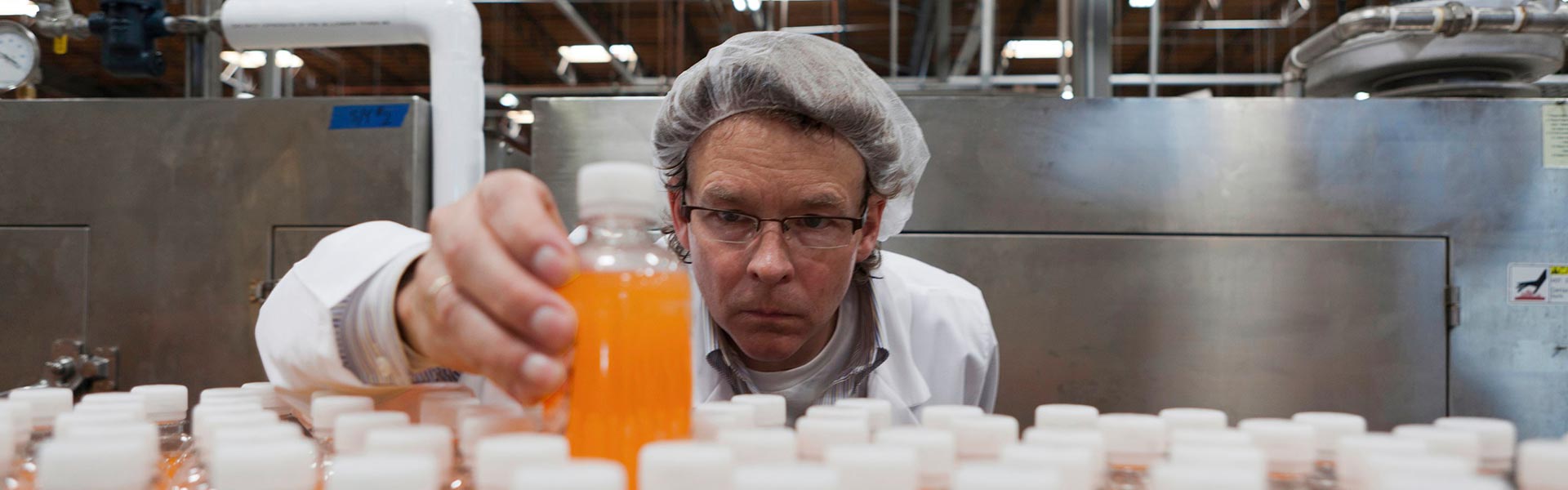 Beverage business employee inspecting bottles.