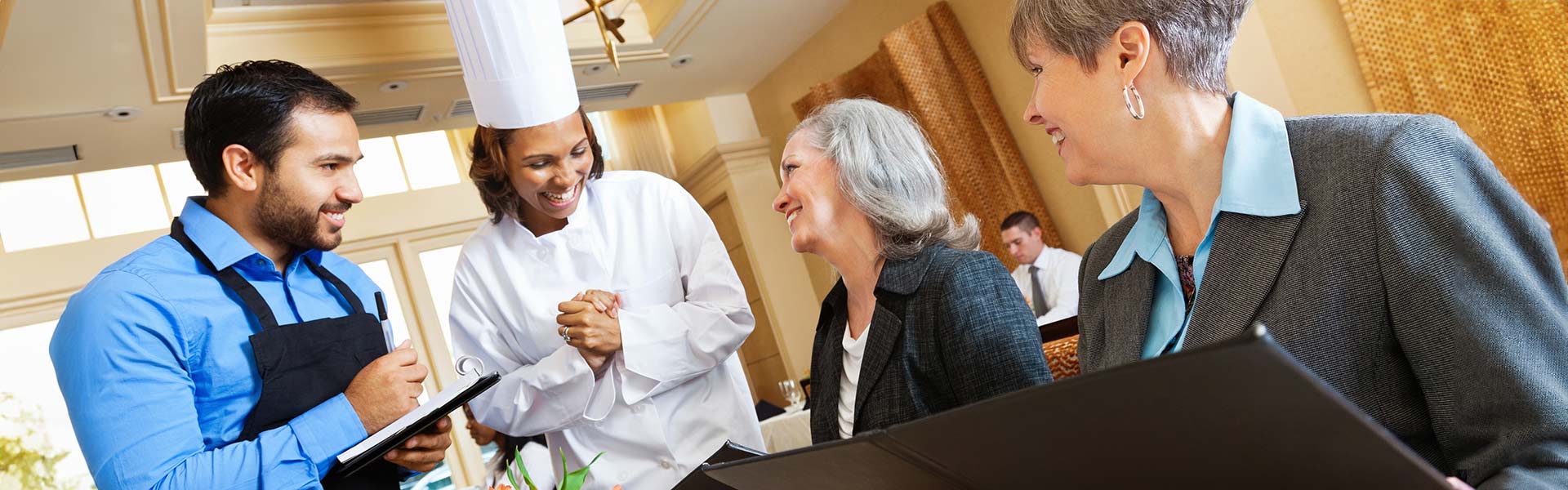 Restaurant chef and waiter helping customers with menu food questions.