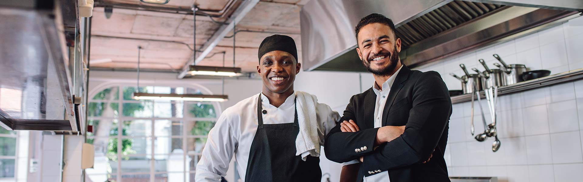 A restaurant owner and professional chef standing in a kitchen.