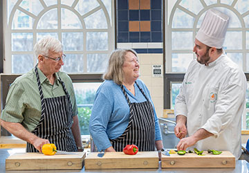 Culinary Therapeutics Master’s Degree Image of two people standing in front of chopping boards watching a chef.