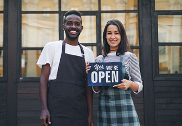 Food Business Master’s Degree Image of two people standing in front of a restaurant with an open sign.